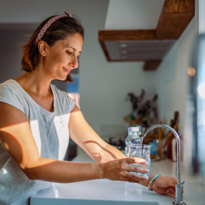 woman filling a glass with filtered water right from the tap