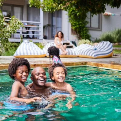 playing with his kids in a pool with their mom watching in summer